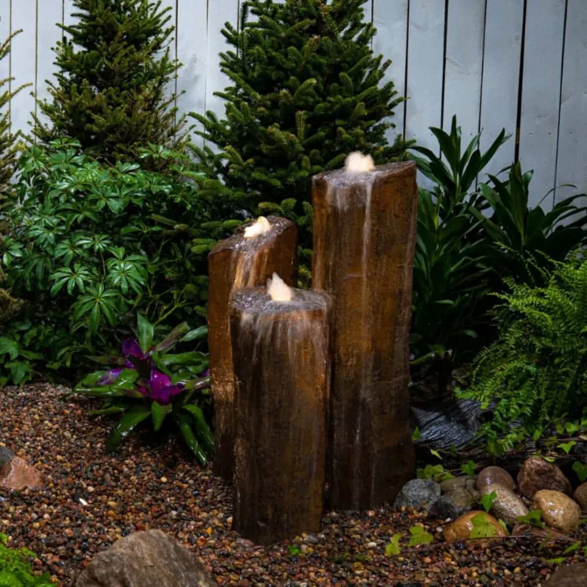 Garden waterfall feature surrounded by lush green plants. - Faux Basalt Column Set of 3