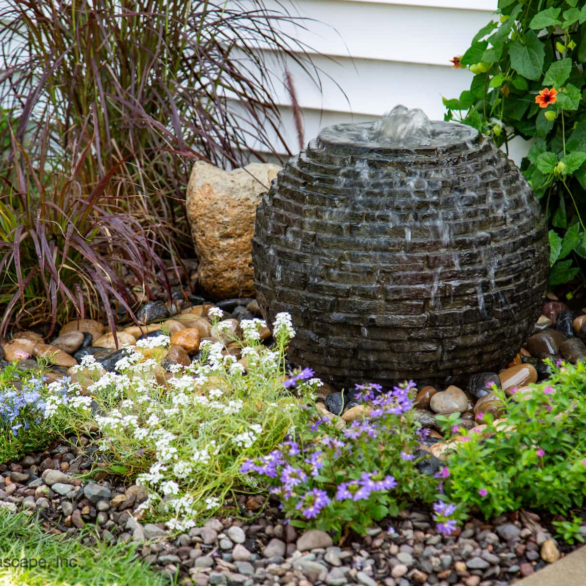 Garden fountain surrounded by colorful flowers.
