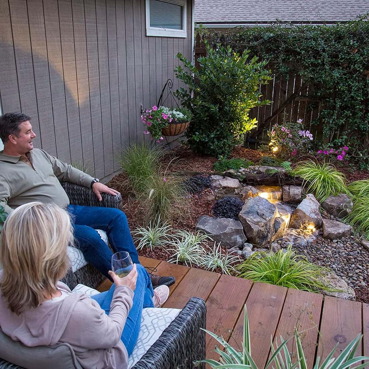 Couple relaxing by backyard pond with lights. - Backyard Waterfall Landscape Fountain Kit