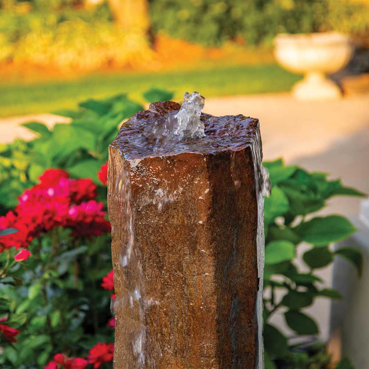 Stone water fountain with red flowers in garden. - Faux Basalt Column Fountain Kit – 24″ H (61 cm)