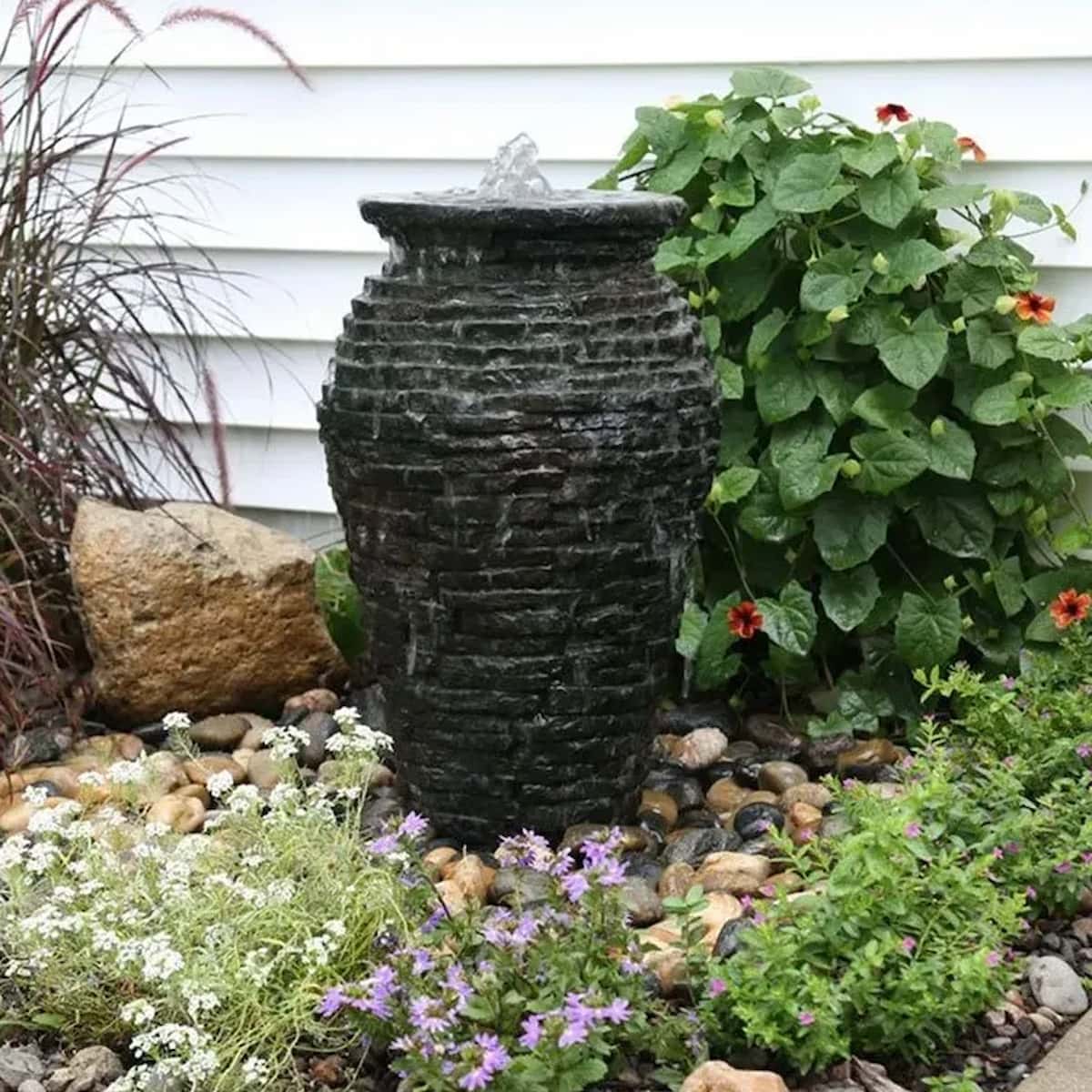 Garden with stone water fountain and blooming plants