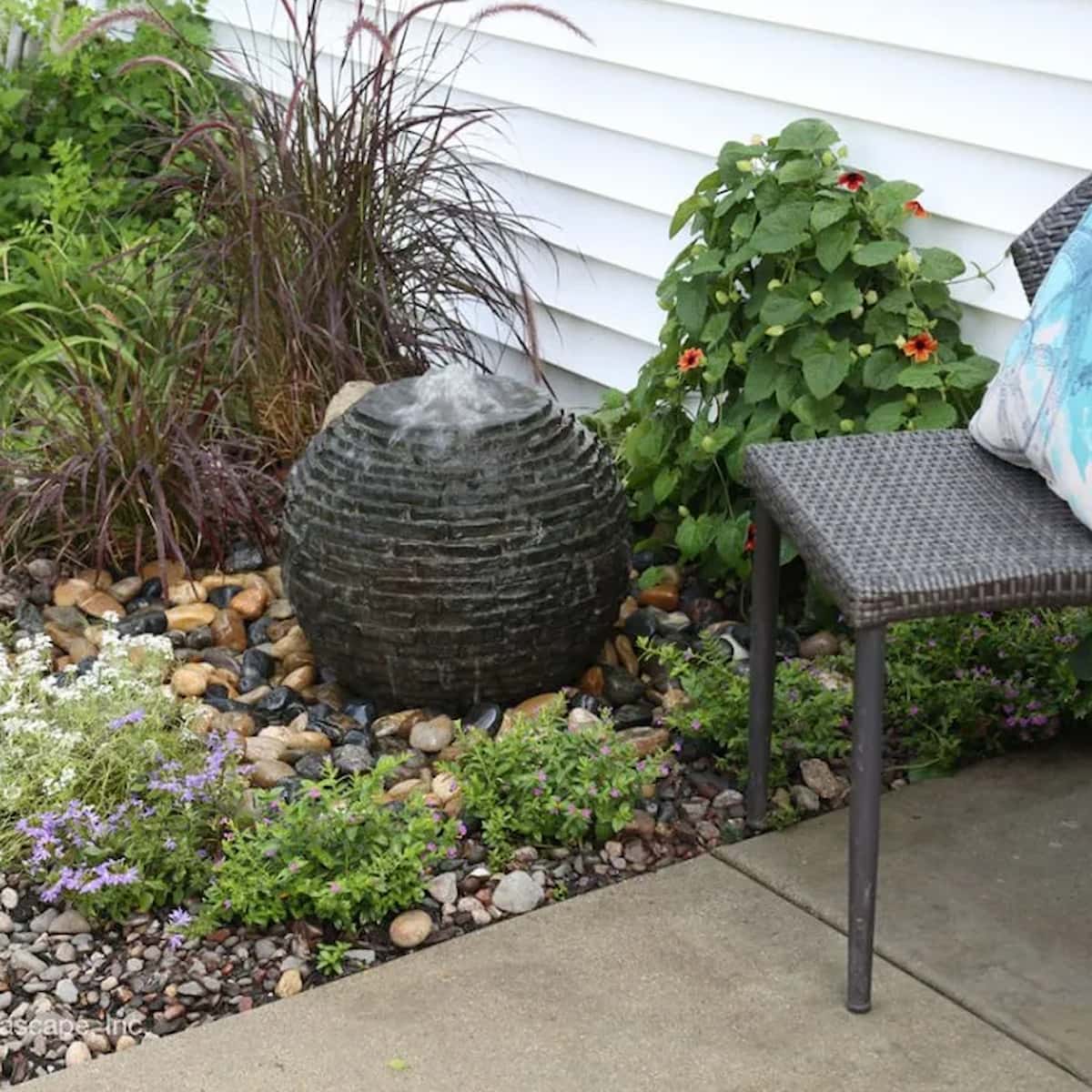 Garden water feature with plants and chair. -Stacked Slate Sphere Fountain Kit – 18″ Dia (46 cm)